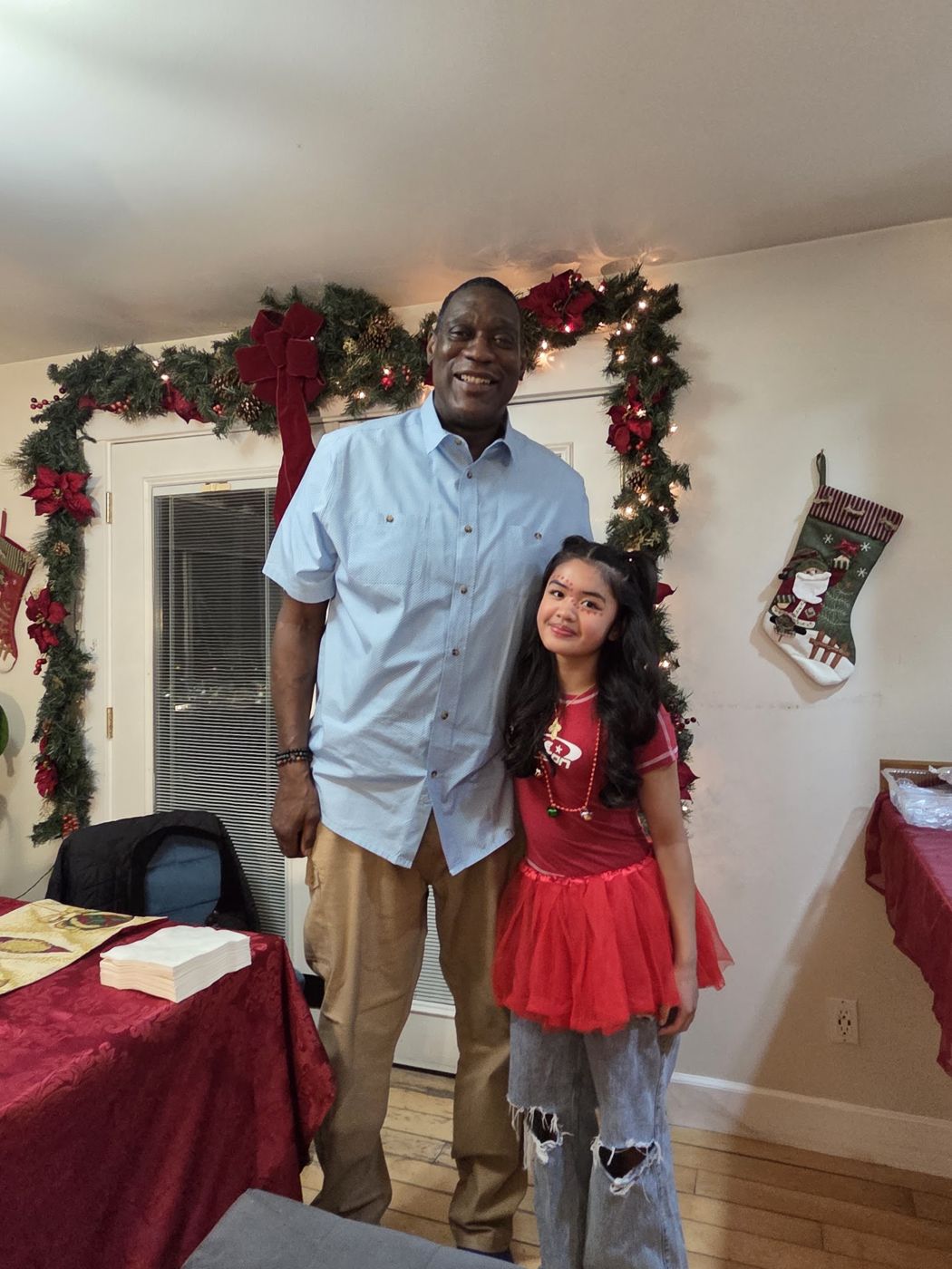 Shawn Kemp with a girl in a red holiday dress by a Christmas garland